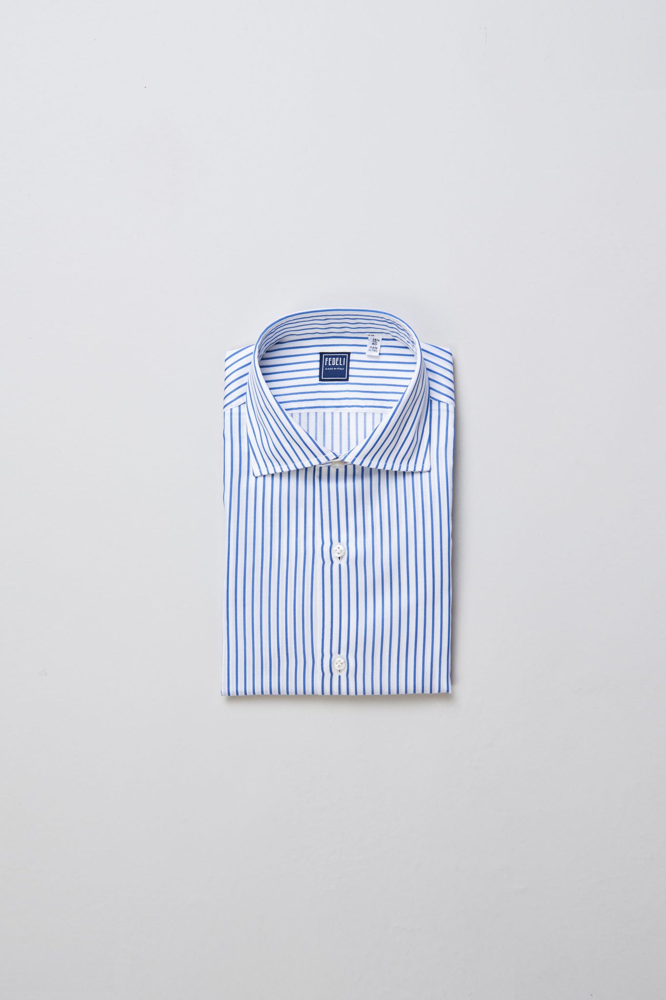 White and blue striped shirt made from Carlo Riva fabric, showcasing meticulous craftsmanship with hand-sewn details.